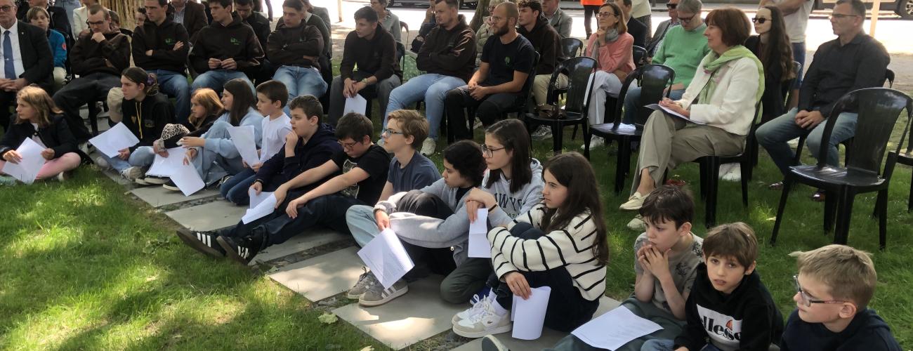 Un groupe d’enfants assis par terre et d’adultes sur des chaises assistent à une cérémonie