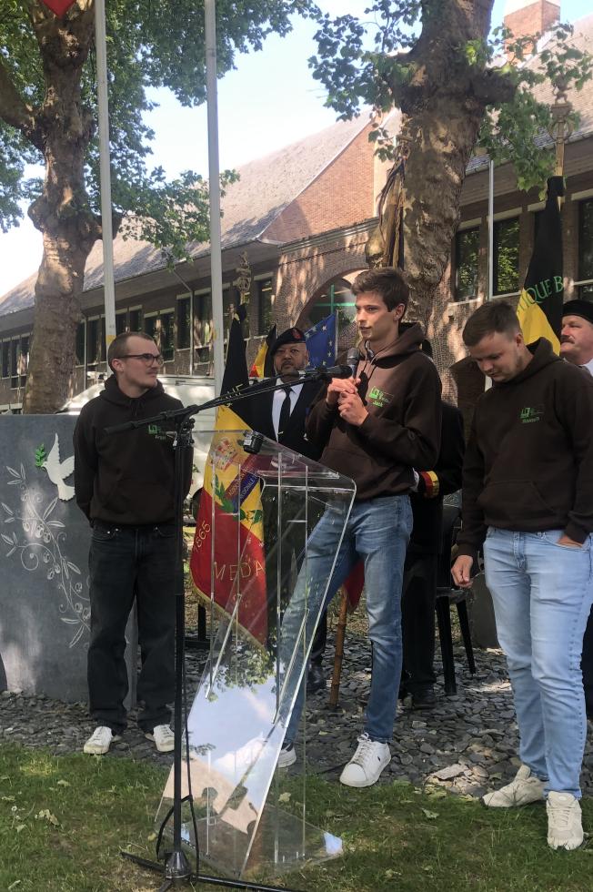 Des élèvres prononcent un discours devant un pupitre, entourés de porte-drapeaux