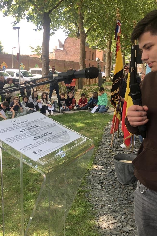 Un étudiant parlant au micro devant un pupitre, avec le public